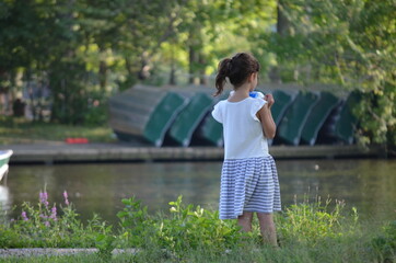 girl holding a bottle, looking at a lake