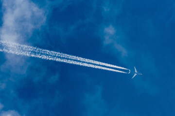 Cargo plane in the sky at the echelon. light clouds and blue sky, condensation trail behind the...