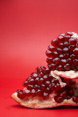Ruby ripe fresh juicy sliced pomegranate isolated on red background