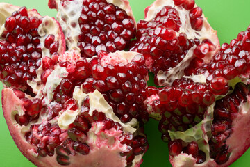 Red ripe fresh juicy sliced pomegranate isolated on green background