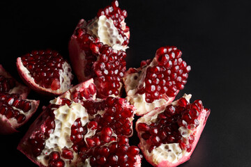 Red ripe fresh juicy sliced pomegranate isolated on black background
