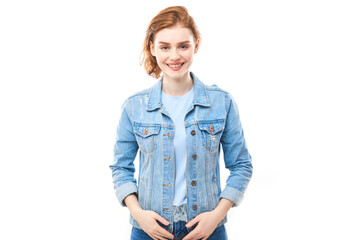 Fototapeta premium Portrait of a young red-haired girl on a white isolated background in jeans. Looks into the camera