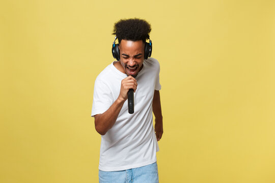 Attractive Young Dark-skinned Man With Afro Haircut In White T Shirt, Gesticulating With Hands And Microphone, Dancing And Singing On Party, Having Fun.