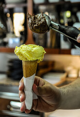 Vertical shot of a person adding another scoop of ice cream on the ice cream cone