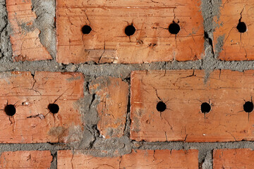 Red cracked brick wall with holes background texture