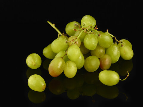 fresh green grapes on dark background with reflection