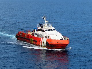 Fototapeta premium Supply boat transfer the cargo for supporting oil and gas industry and moving cargo from the boat to the platform. Boat is waiting transfer cargo and crews to platform. 
