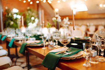 Banquet table in the restaurant, the preparation before the banquet. The work of professional florists in emerald color. Wedding, birthday, party, event concept.