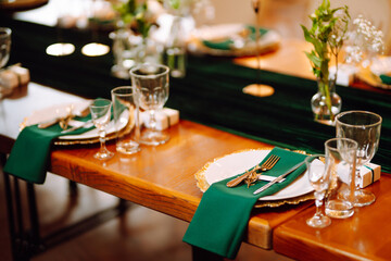 Banquet table in the restaurant, the preparation before the banquet. The work of professional florists in emerald color. Wedding, birthday, party, event concept.
