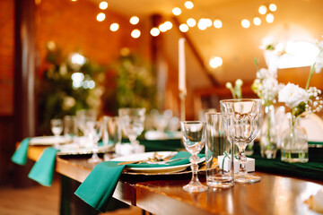 Banquet table in the restaurant, the preparation before the banquet. The work of professional florists in emerald color. Wedding, birthday, party, event concept.
