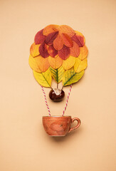 Colorful hot air balloon made of autumn leaves flying with a cup  coffee. Creative minimal autumn idea