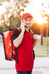 Male courier with isothermal food case box on electric scooter arrives to the entrance to the house...