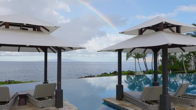 Rainbow over the ocean and infinity pool - pan down