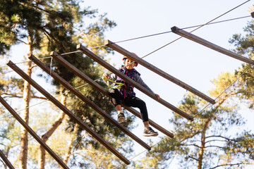 the girl in the orange helmet in the adventure Park holds on to the ropes