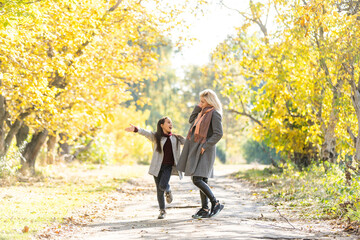 Fototapeta premium happy family: mother and child little daughter play on autumn walk in nature outdoors
