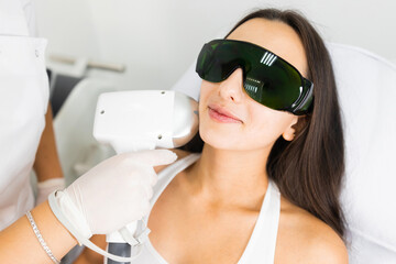 Naklejka premium Laser hair removal for facial skin. Woman in epilation salon