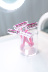 Fototapeta na wymiar Set of disposable pink female razors in a glass