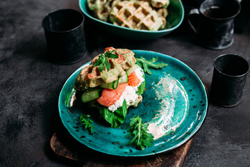 Belgian waffles with salmon, cucumber and egg in a plate