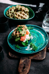 Belgian waffles with salmon, cucumber and egg in a plate