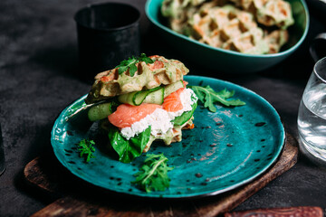 Belgian waffles with salmon, cucumber and egg in a plate