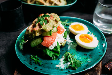 Belgian waffles with salmon, cucumber and egg in a plate