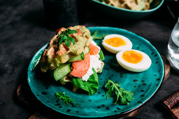 Belgian waffles with salmon, cucumber and egg in a plate