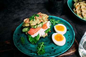 Belgian waffles with salmon, cucumber and egg in a plate