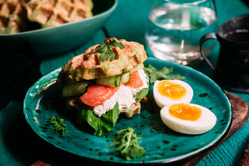 Belgian waffles with salmon, cucumber and egg in a plate
