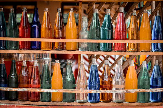 Hubli, Karnataka, India - July 31, 2021: Different colours of soda glasses are organised in rows and kept on shelves on a storefront.
