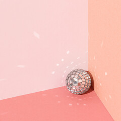 Disco ball against bright pink and peach background with copy space. Minimal party concept.