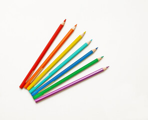 bright colorful pencils in the amount of seven pieces for drawing, lie on a white sheet of paper.