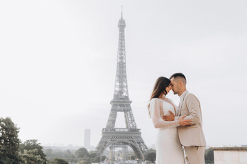 Fototapeta na wymiar Wedding couple kissing in front of the Eiffel tower in Paris, France. A man kisses his woman.
