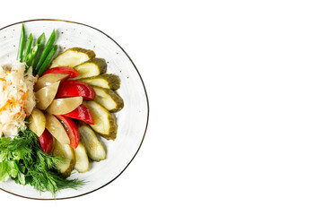 Chopped pickles on a plate. Fermented cabbage, tomatoes, cucumbers and peppers with a bunch of greens. Isolated on white background. Space for text.
