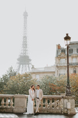 Beautiful romantic couple holding each other by hands in front of the Eiffel tower in Paris, France.