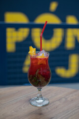 close up of a Red Cocktail on a wooden table with yellow letters in the background
