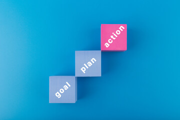 Business concept. Goal, plan, action written on toy blocks on dark blue background