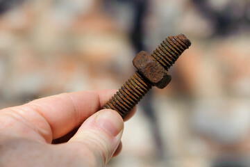 old rusty bolt, iron rod with screw threads, in hand. Rusted mechanical components. holding threaded bolt and nut. dismantling concept, difficult to unscrew, non-removable. isolated, macro photo