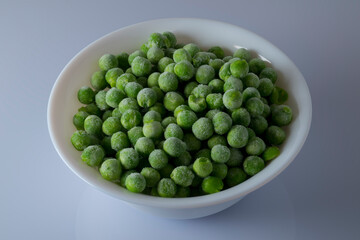Bowl full of frozen green peas, light background