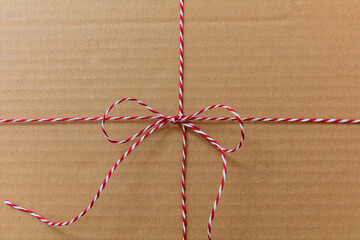 Christmas string and bow on kraft paper background. Red white striped twine holiday gift decoration.