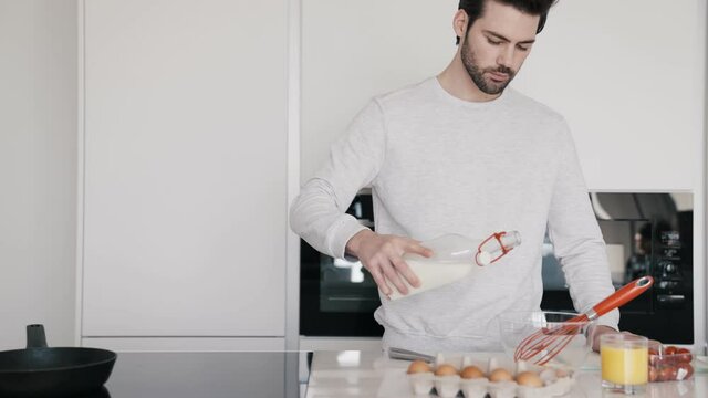 Close-up view of the positive man adding milk to omelet for breakfast