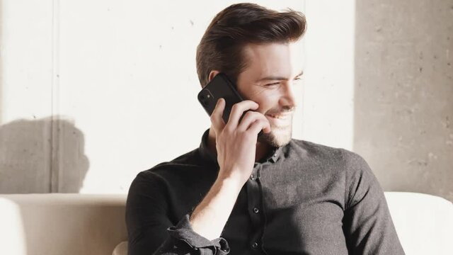 Smiling businessman talking on the phone and looking to the side at home