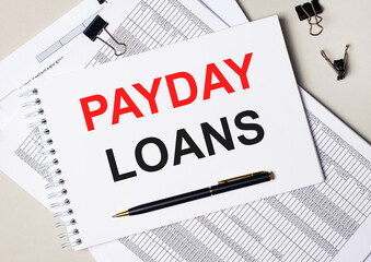On the desktop there are documents, pen, black paper clips and a notebook with the text PAYDAY...