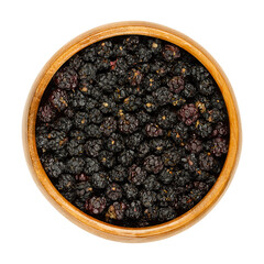 Dried ripe European blackberries in a wooden bowl. Air dried wild brambles, Rubus fruticosus, a sweet fruit, used for tea additive. Close-up from above, isolated on white background, macro food photo.