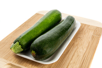 two green zucchini squash in a grocery store plastic foam tray isolated on white