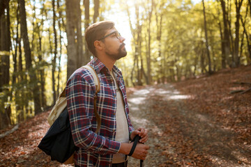 Caucasian hipster male model outdoors in nature. Colorful landscape with trees, rural road, orange...