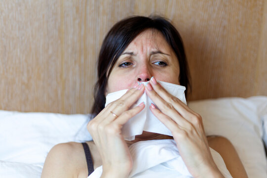 Girl in bed, Sinus pain, sinus pressure, sinusitis. Sad woman holding her nose and head because sinus pain. Sinus ache causing very paintful headache.