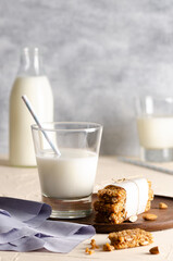 Two glasses and a bottle of milk and cereal bars with a light blue napkin. 