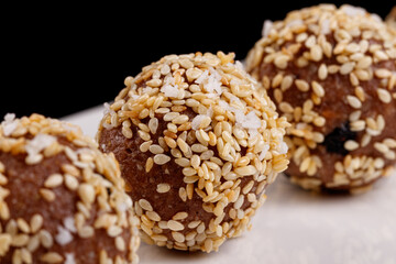 Beautiful candies with sesame seeds on a white plate on a black background