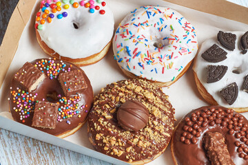 Caja de donas clásicas decoradas con diferentes topping o dulces.