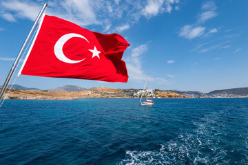 The flag of Turkey is flying on a boat over the sea - obrazy, fototapety, plakaty